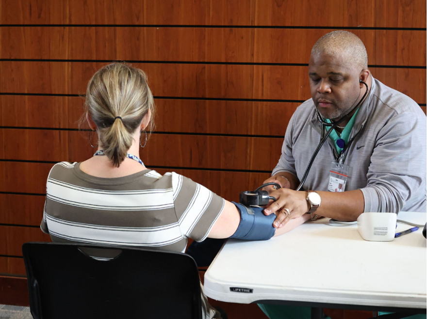 family nurse practitioner performs a manual blood pressure check during a health screening